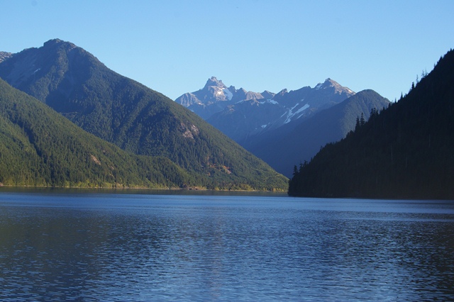 The pristine, calm waters of Chilliwack Lake reflecting the surrounding old-growth forest and mountain peaks at S⨱ótsaqel / Chilliwack Lake Provincial Park.