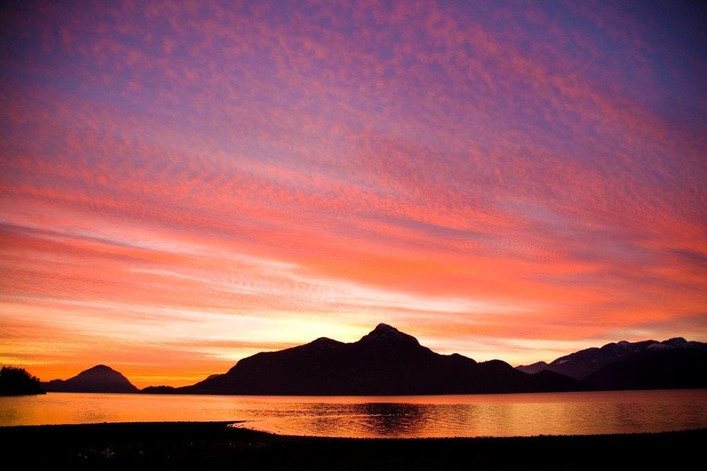 Vibrant orange and pink sunset sky reflecting over the calm waters of Porteau Cove at Porteau Cove Provincial Park.