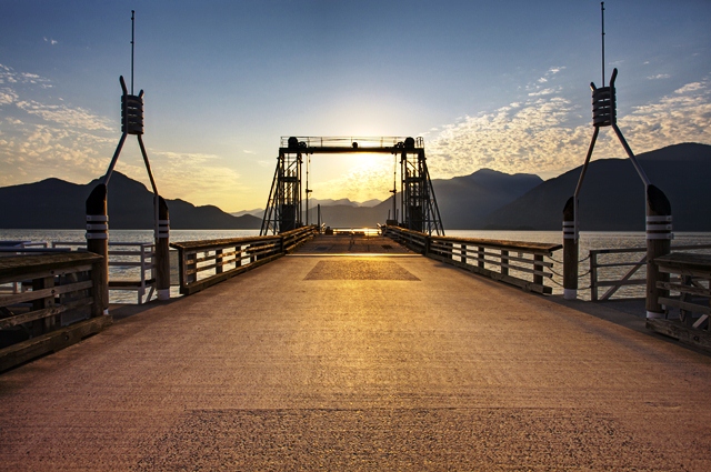 View from the start of the pier looking down the length of the Porteau Cove dock, with mountains visible in the distance.